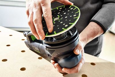 Remeselník nasadzuje brúsny tanier na brúsku Festool