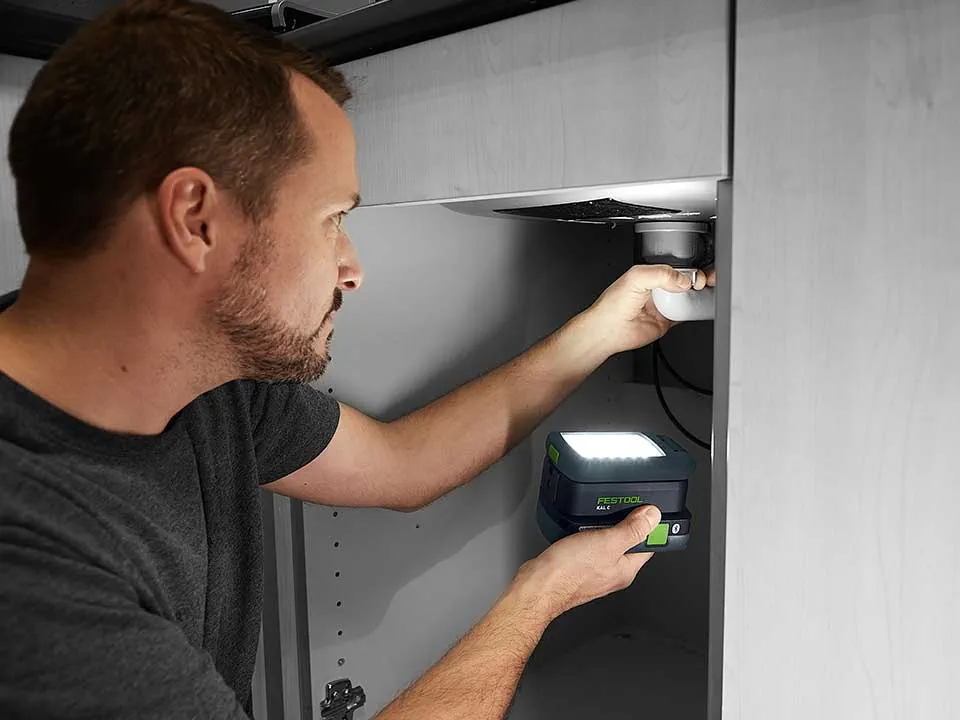 Muž osvetľuje pripojenie umývadla so systémom SYSLITE KAL 2